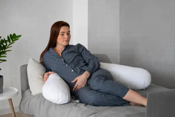 mujer con un cojín ergonómico en la lumbar recostada en la cama 